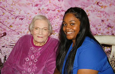 Smiling patient with nurse in front of pink wall